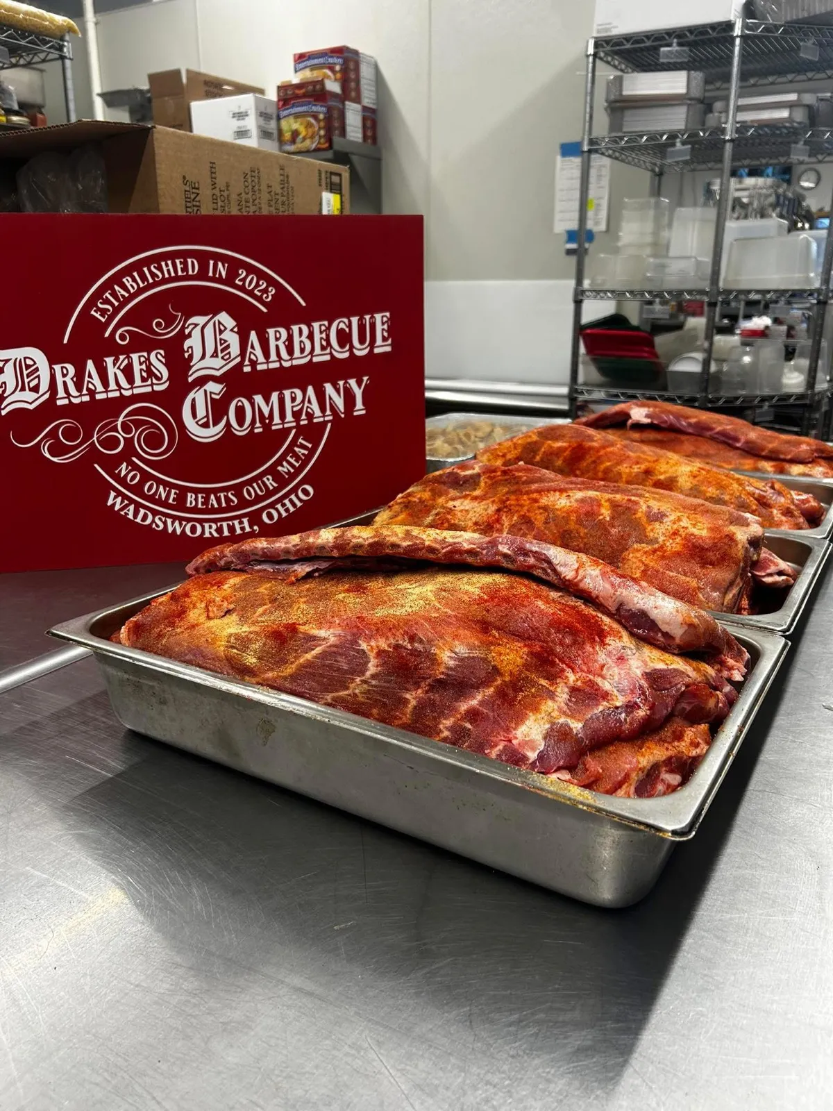 Fresh-rubbed ribs beside the Drake's Barbecue Company sign in the prep kitchen